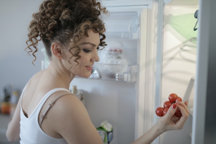 Donna cerca i pomodori nel frigo - Fonte Pexels