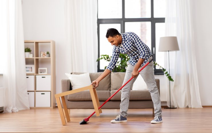 Uomo passa la scopa in casa - Fonte AdobeStock