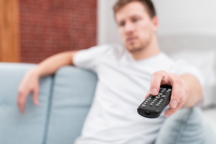 Uomo che guarda televisione con un telecomando in mano 