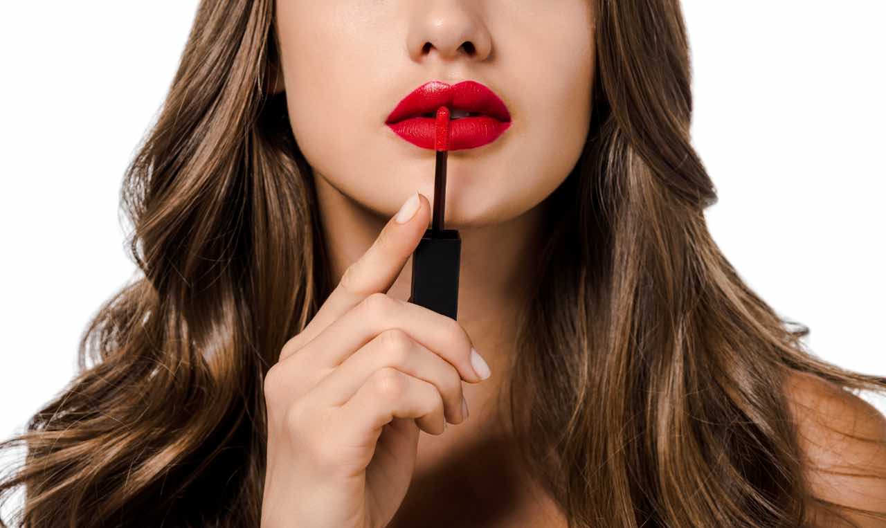 Donna che si applica del rossetto rosso 