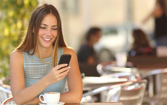 Ragazza che guarda telefono in un bar