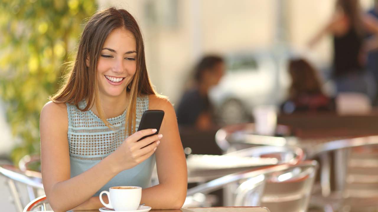 Ragazza che guarda telefono in un bar